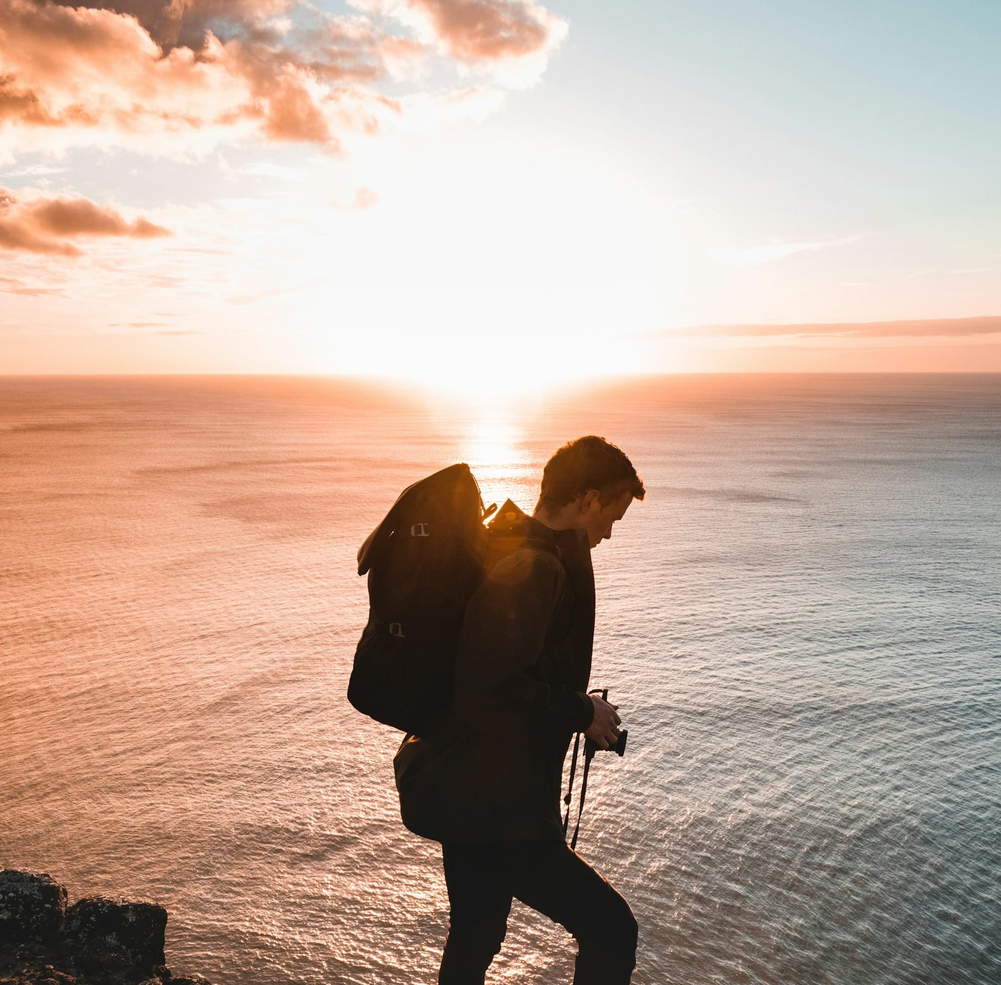 man standing near the shore during sunset